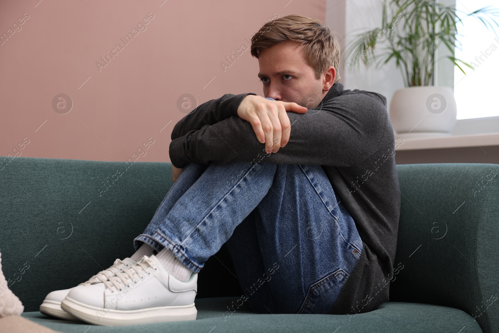 Man suffering from paranoia on sofa at home Photo of Man suffering from paranoia on sofa at home