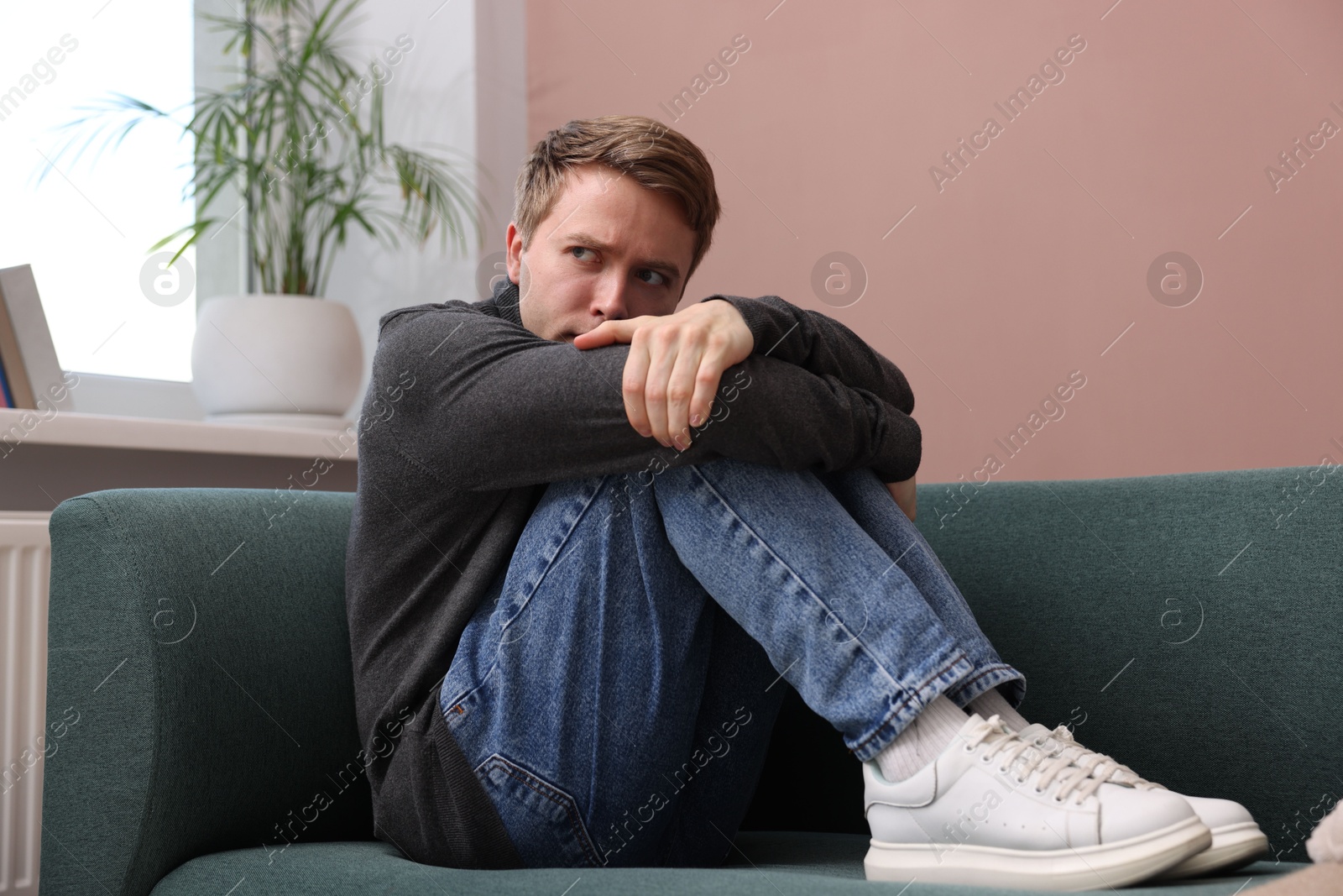 Man suffering from paranoia on sofa at home Photo of Man suffering from paranoia on sofa at home
