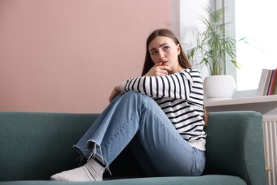 Photo of Woman suffering from paranoia on sofa at home