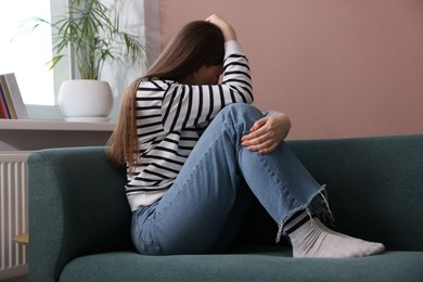 Photo of Woman suffering from paranoia on sofa at home
