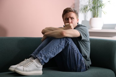 Photo of Man suffering from paranoia on sofa at home