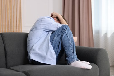 Photo of Man suffering from paranoia on sofa at home