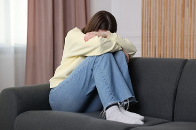 Photo of Woman suffering from paranoia on sofa at home