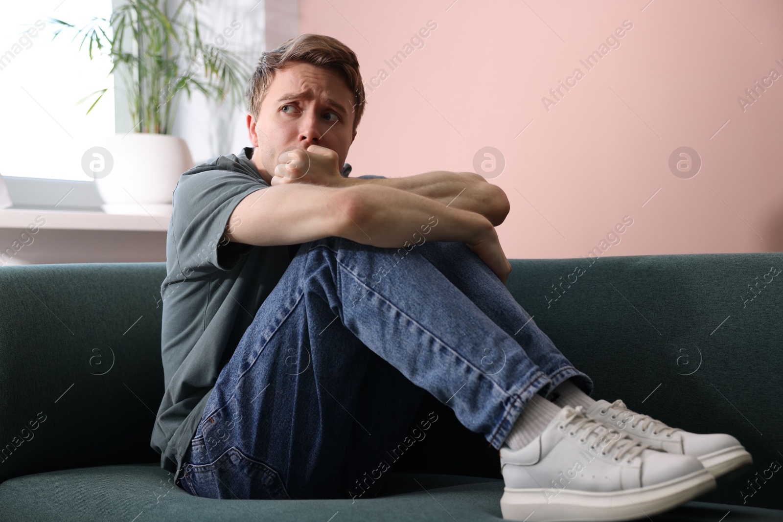 Man suffering from paranoia on sofa at home Photo of Man suffering from paranoia on sofa at home