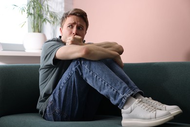 Photo of Man suffering from paranoia on sofa at home
