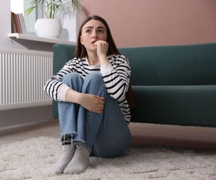 Photo of Woman suffering from paranoia on floor at home
