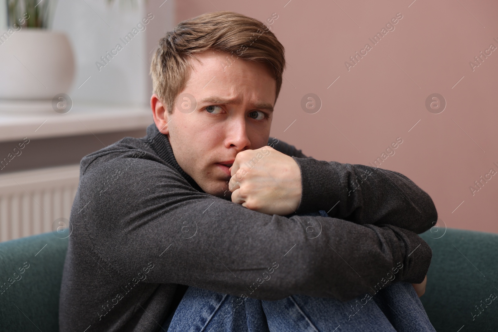 Man suffering from paranoia on sofa at home Photo of Man suffering from paranoia on sofa at home