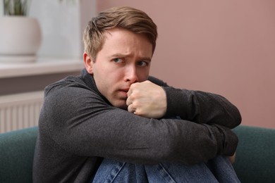 Photo of Man suffering from paranoia on sofa at home