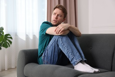 Photo of Man suffering from paranoia on sofa at home