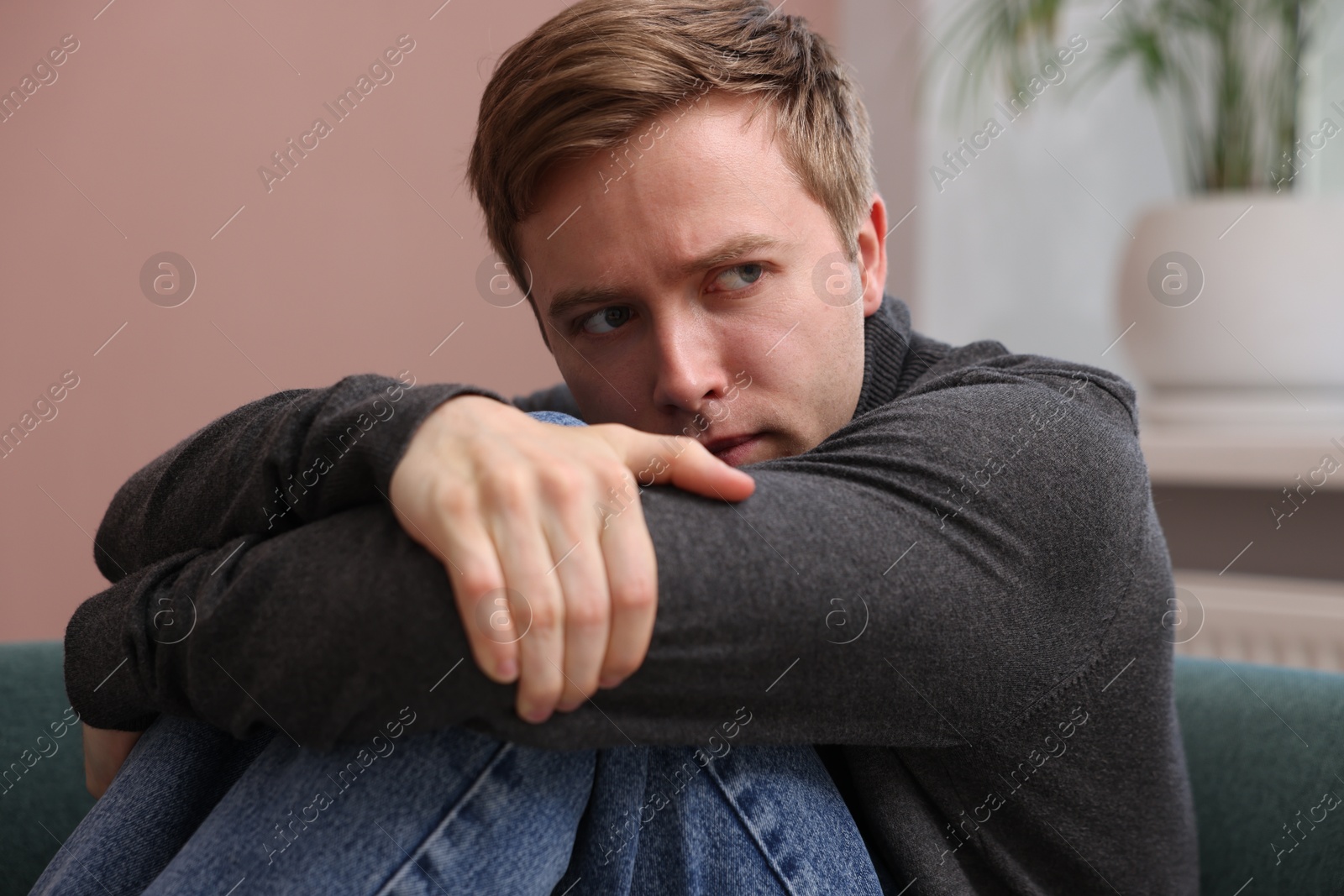 Scared man suffering from paranoia at home Photo of Scared man suffering from paranoia at home