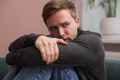 Photo of Scared man suffering from paranoia at home