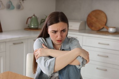 Photo of Worried woman suffering from paranoia in kitchen