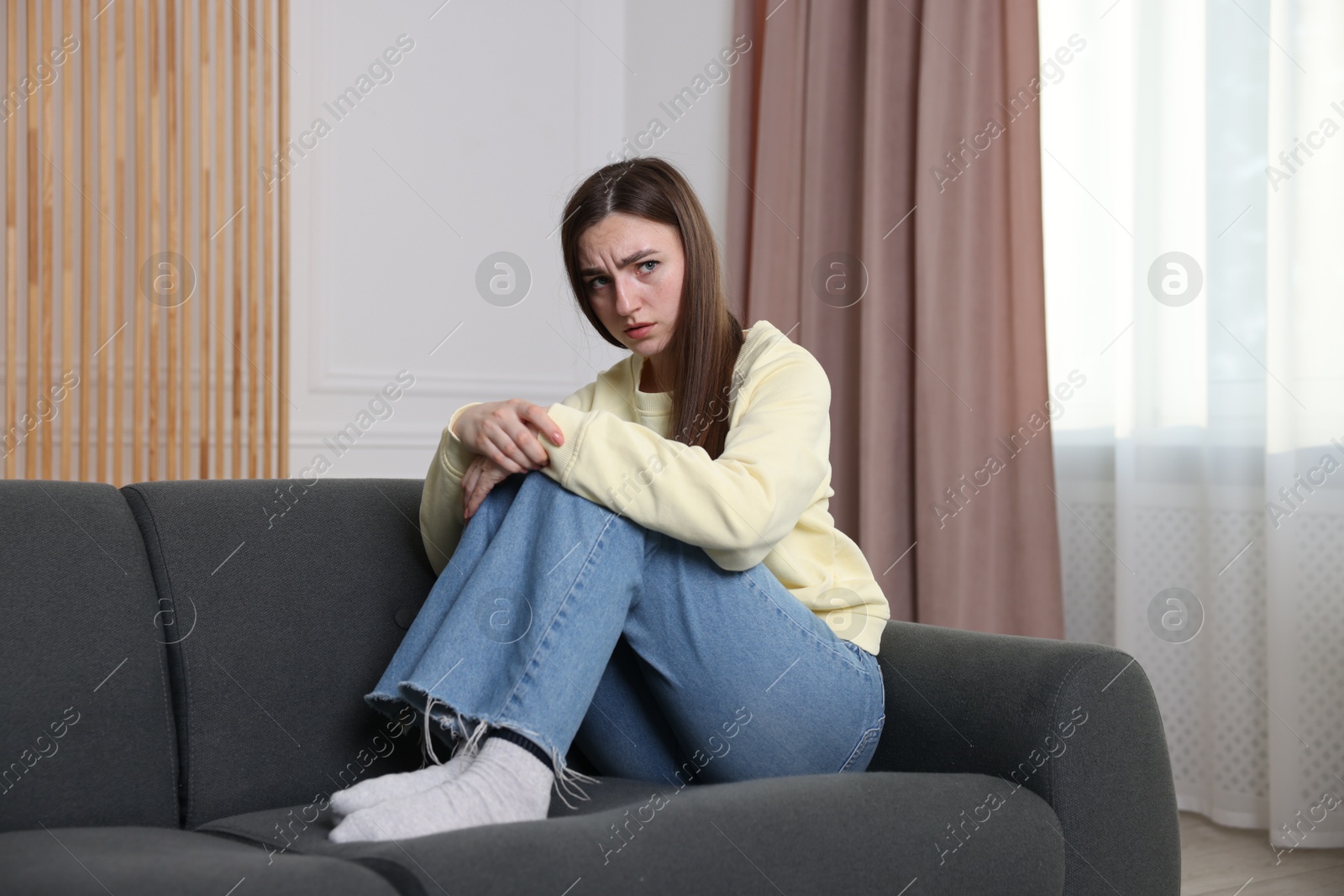 Photo of Woman suffering from paranoia on sofa at home