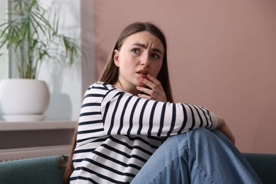 Photo of Woman suffering from paranoia on sofa at home