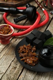 Photo of Hookah, coal and fresh fruits on wooden table, closeup