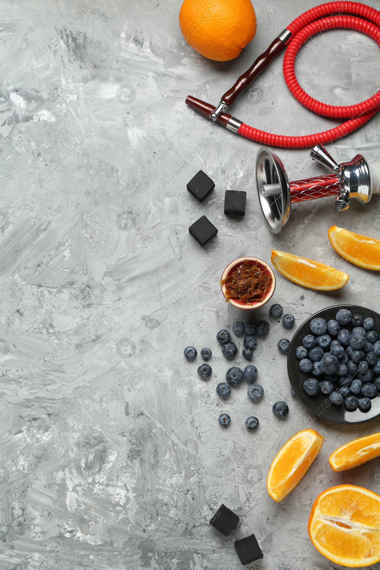 Photo of Hookah, coal and fresh fruits on grey table, flat lay. Space for text