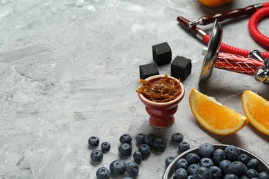 Photo of Hookah, coal and fresh fruits on grey table, closeup. Space for text