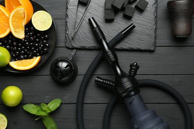 Photo of Hookah, coal and fresh fruits on black wooden table, flat lay
