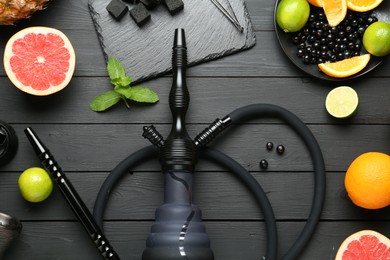 Photo of Hookah, coal and fresh fruits on black wooden table, flat lay