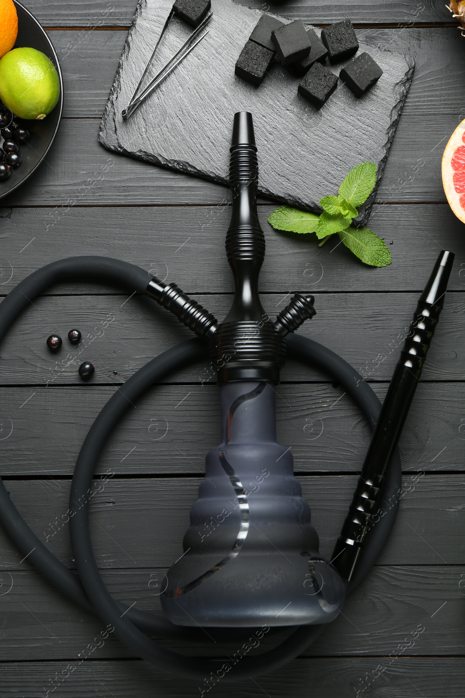 Photo of Hookah, coal and fresh fruits on black wooden table, flat lay