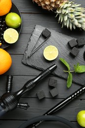 Photo of Hookah, coal and fresh fruits on black wooden table, flat lay