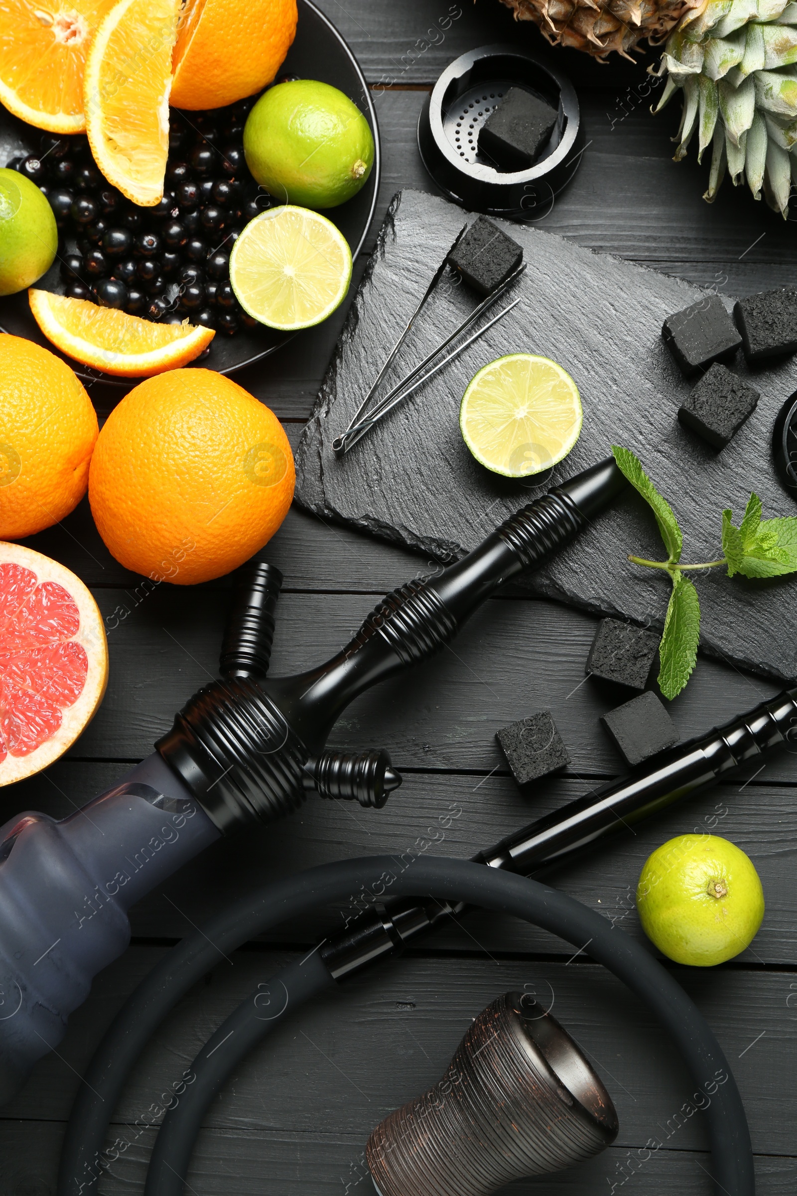Photo of Hookah, coal and fresh fruits on black wooden table, flat lay