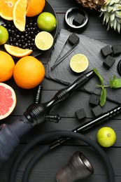 Photo of Hookah, coal and fresh fruits on black wooden table, flat lay