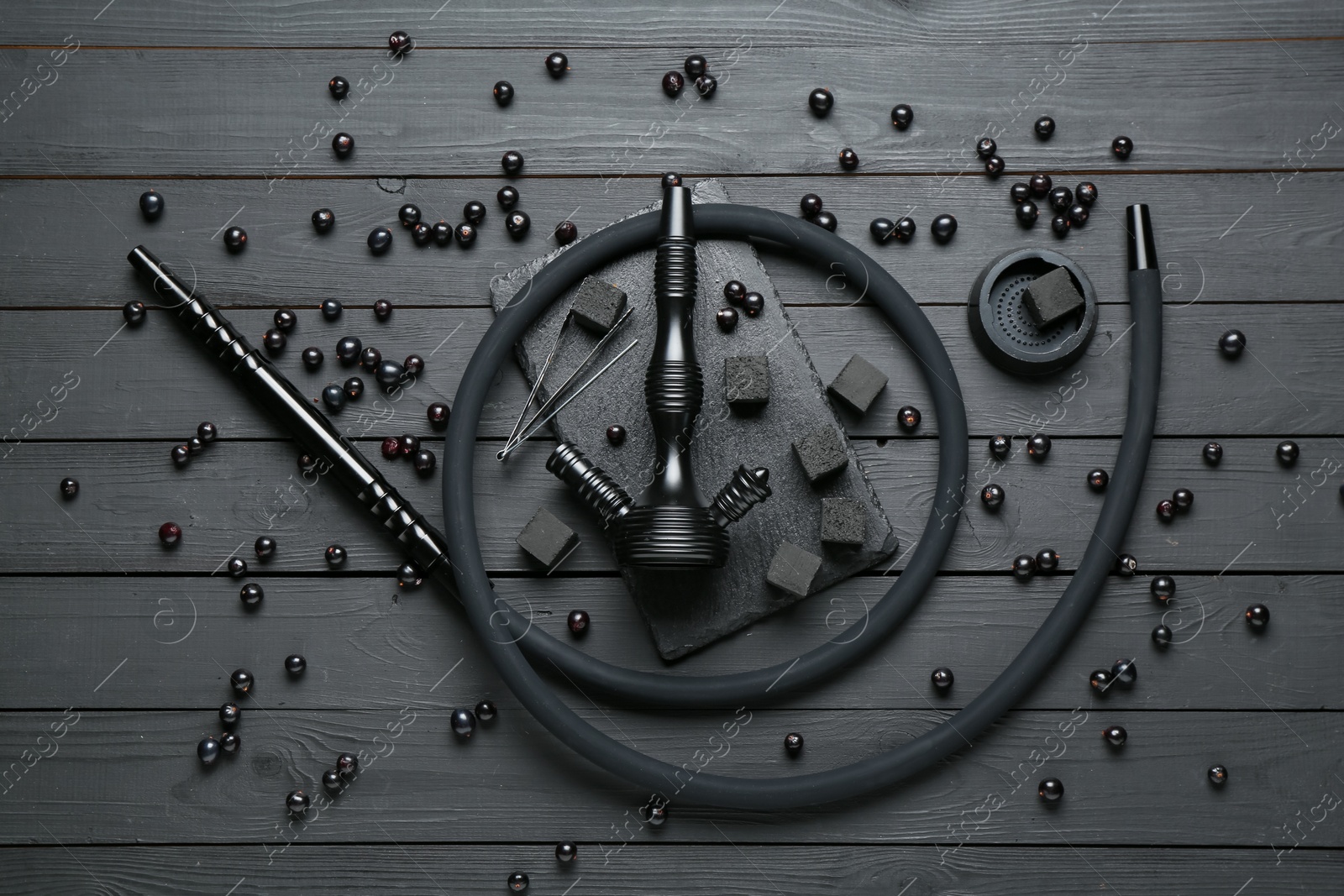Photo of Hookah, coal and currants on black wooden table, flat lay