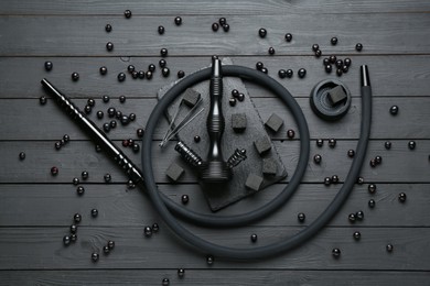 Photo of Hookah, coal and currants on black wooden table, flat lay