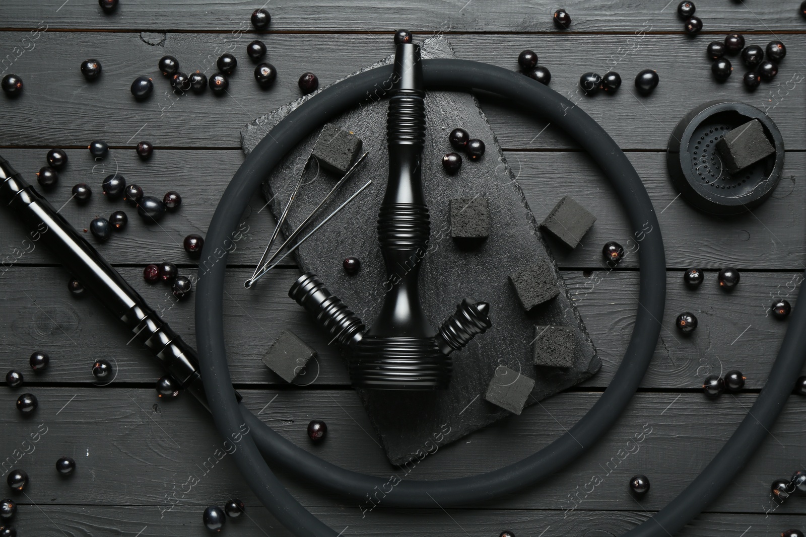 Photo of Hookah, coal and currants on black wooden table, flat lay