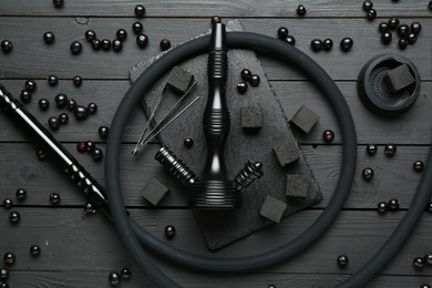 Photo of Hookah, coal and currants on black wooden table, flat lay
