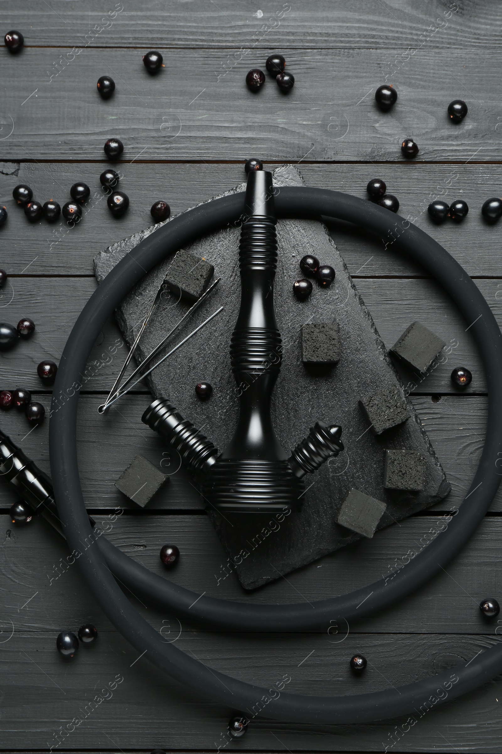 Photo of Hookah, coal and currants on black wooden table, flat lay