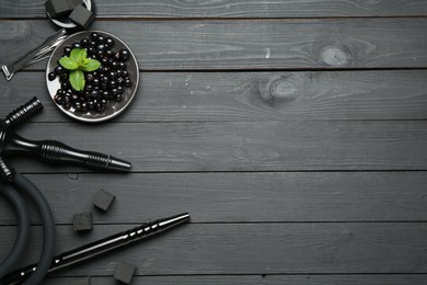 Photo of Hookah, coal, mint and currants on black wooden table, flat lay. Space for text