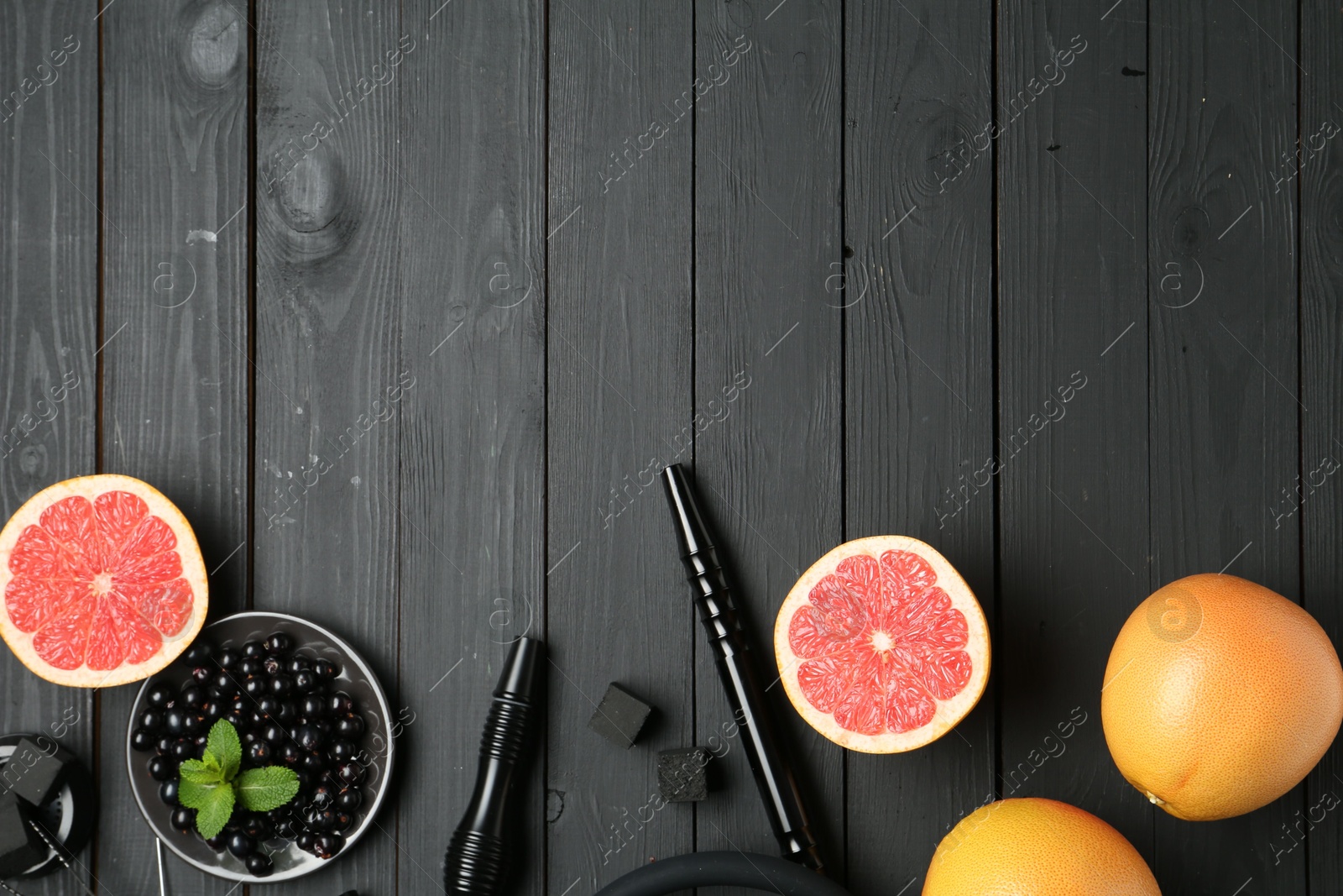 Photo of Hookah, coal and fresh fruits on black wooden table, flat lay. Space for text