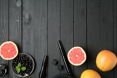Photo of Hookah, coal and fresh fruits on black wooden table, flat lay. Space for text