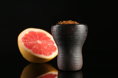 Photo of Hookah bowl with smoke and grapefruit on black table, closeup