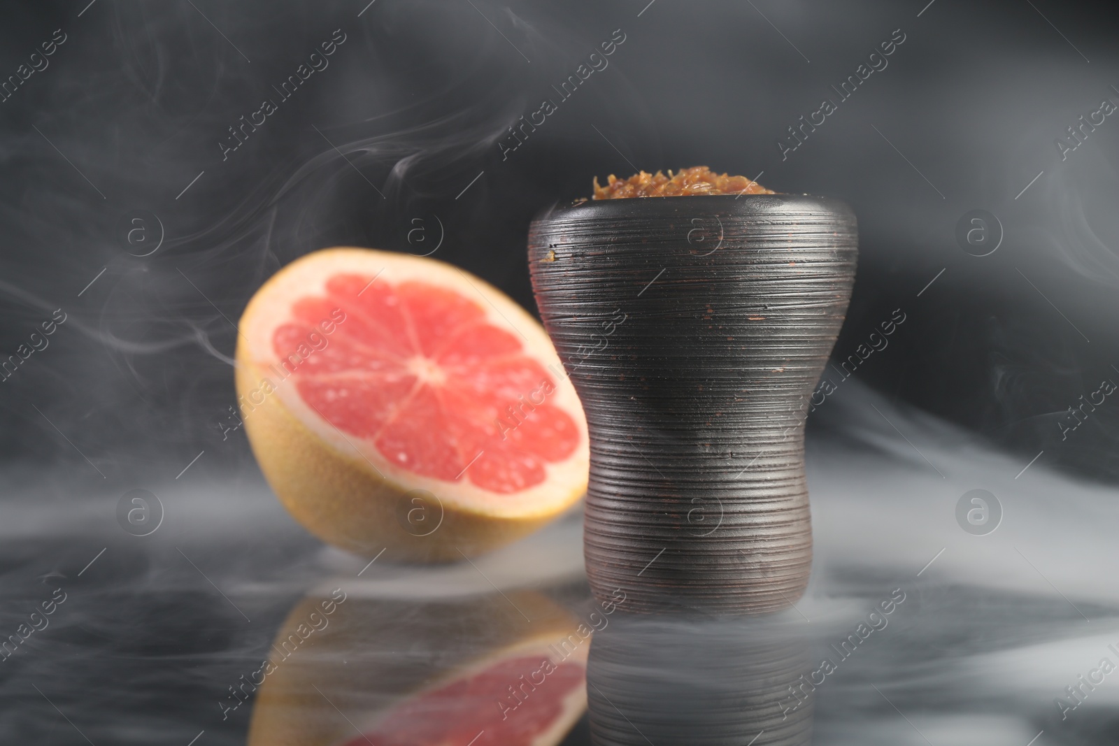 Hookah bowl with smoke and grapefruit on black table, closeup Photo of Hookah bowl with smoke and grapefruit on black table, closeup
