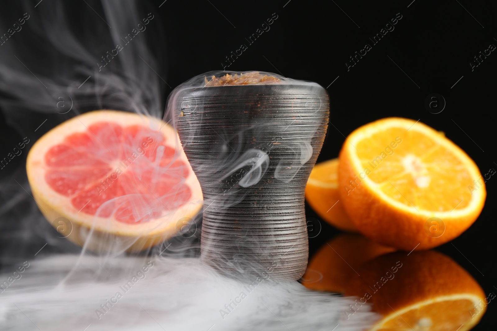Hookah bowl with smoke and fruits on black table, closeup Photo of Hookah bowl with smoke and fruits on black table, closeup