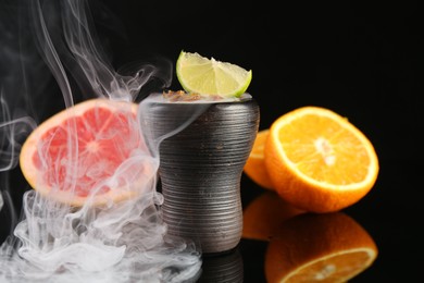 Photo of Hookah bowl with smoke and fruits on black table, closeup
