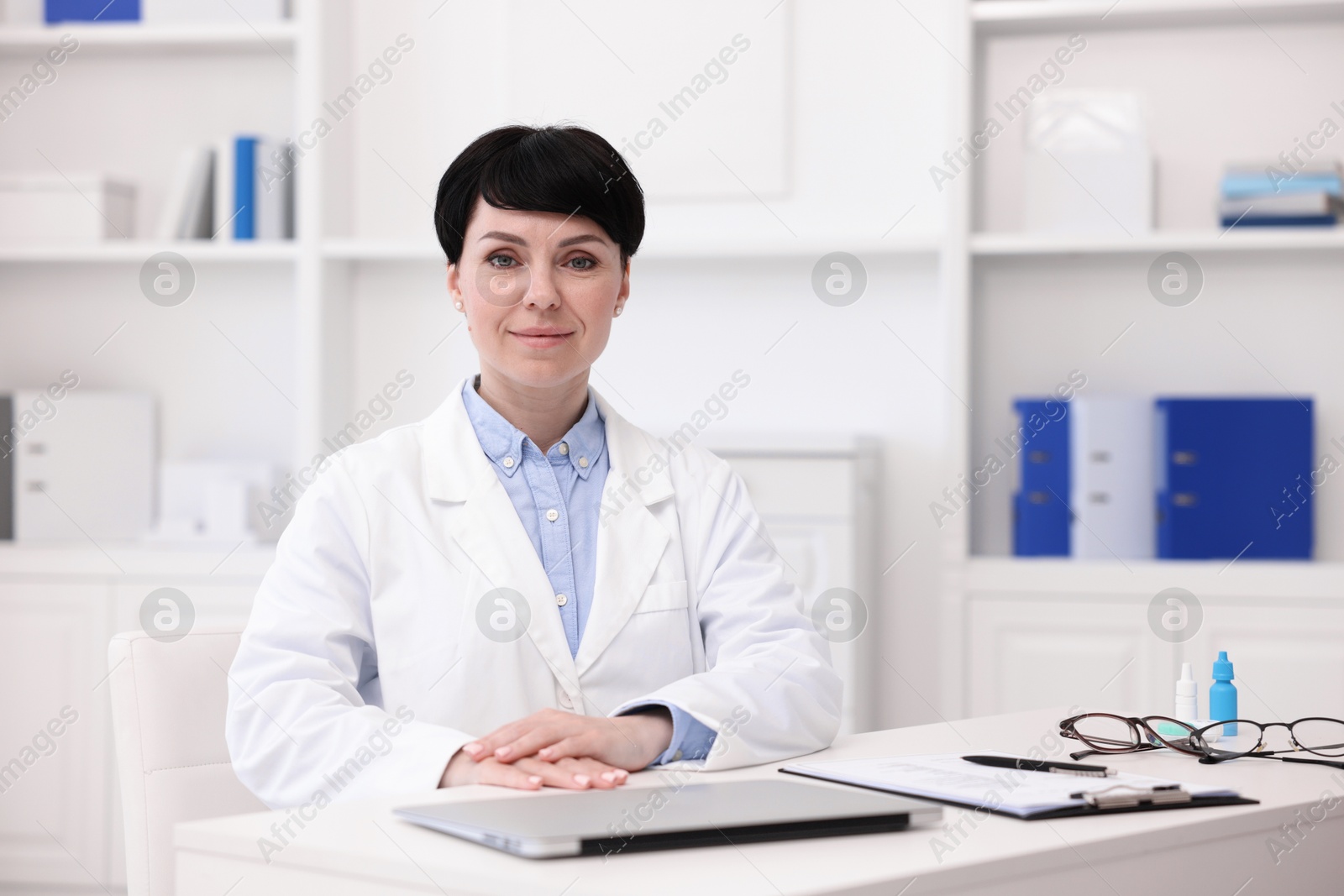 Portrait of professional ophthalmologist at white table in clinic Photo of Portrait of professional ophthalmologist at white table in clinic