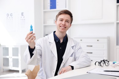 Photo of Portrait of professional ophthalmologist with eye drops at white table in clinic