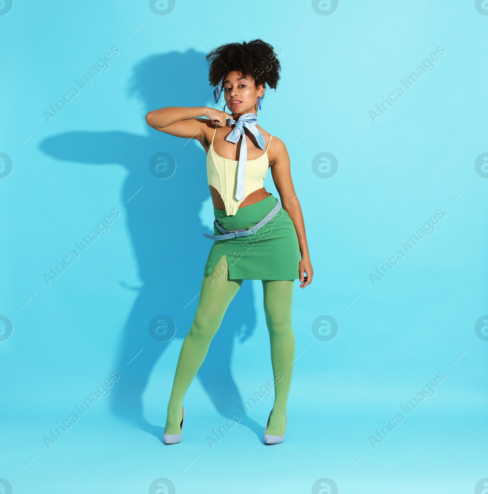 Fashionable portrait of beautiful Brazilian woman in stylish outfit on light blue background Photo of Fashionable portrait of beautiful Brazilian woman in stylish outfit on light blue background