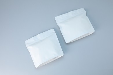 Photo of Two zipper stand-up pouches on light grey background, flat lay. Mockup for design