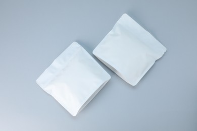 Photo of Two zipper stand-up pouches on light grey background, flat lay. Mockup for design