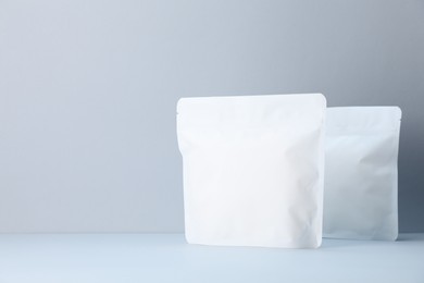 Photo of Two zipper stand-up pouches on light grey background. Mockup for design