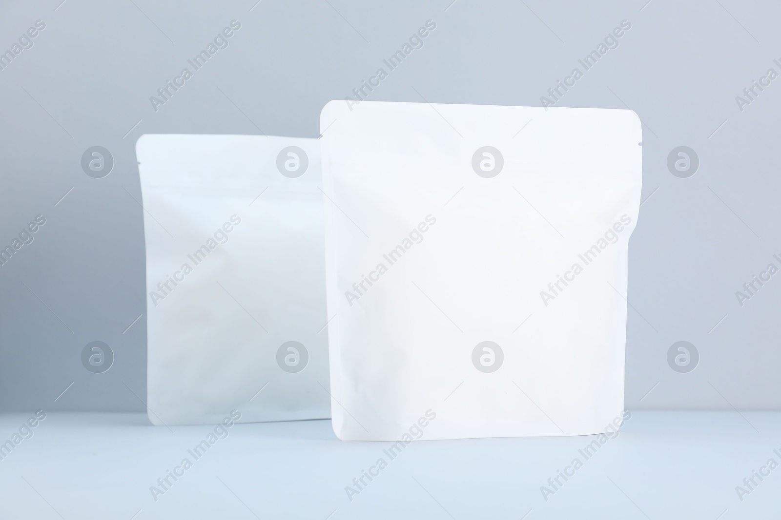 Two zipper stand-up pouches on light grey background. Mockup for design Photo of Two zipper stand-up pouches on light grey background. Mockup for design