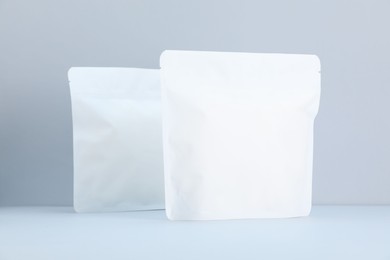 Photo of Two zipper stand-up pouches on light grey background. Mockup for design