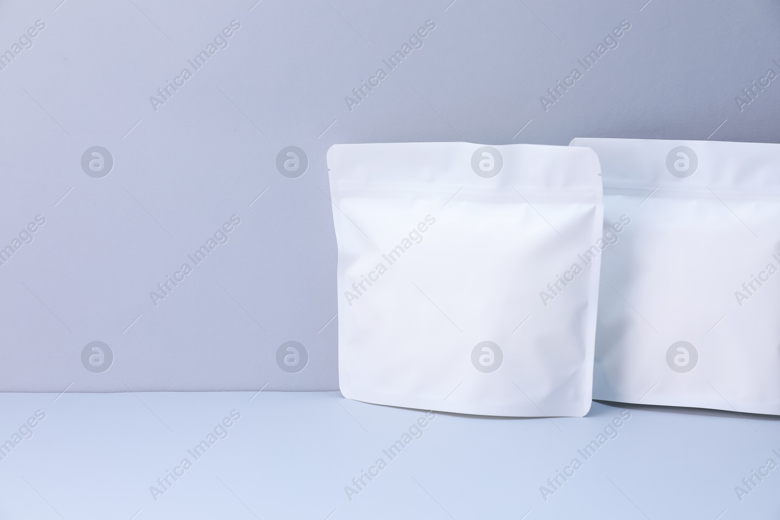 Two zipper stand-up pouches on light grey background. Mockup for design Photo of Two zipper stand-up pouches on light grey background. Mockup for design