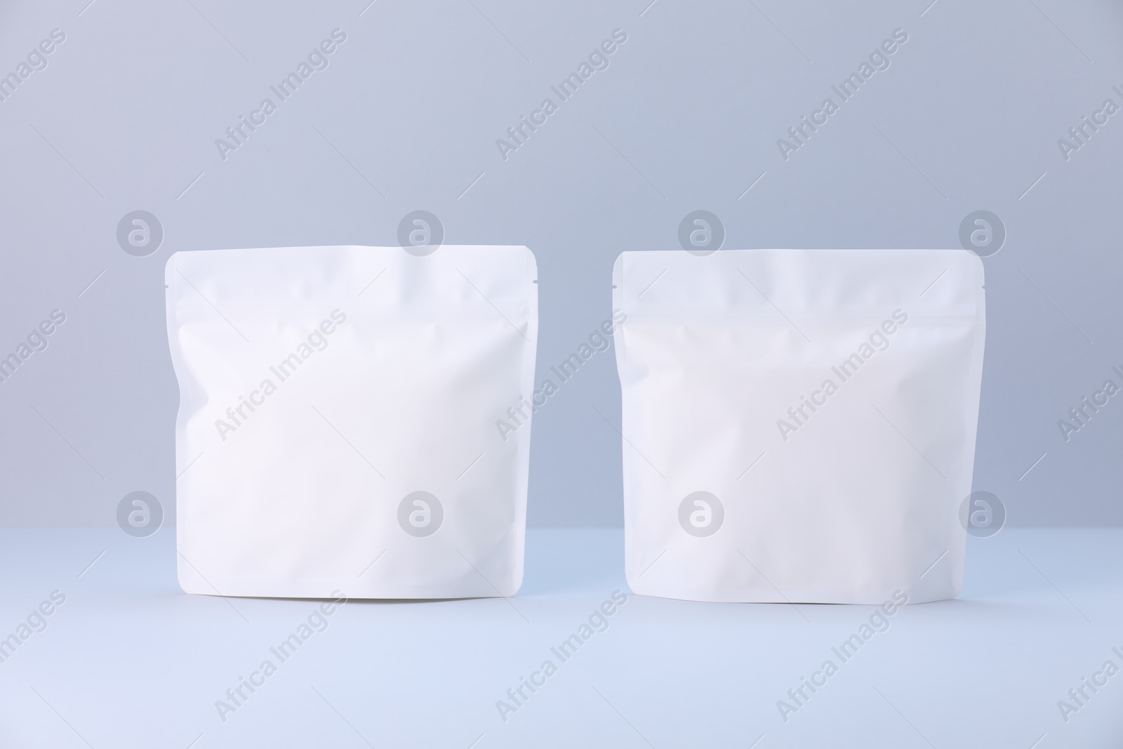 Two zipper stand-up pouches on light grey background. Mockup for design Photo of Two zipper stand-up pouches on light grey background. Mockup for design