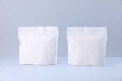 Photo of Two zipper stand-up pouches on light grey background. Mockup for design